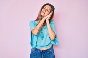 Beautiful caucasian woman wearing casual clothes sleeping tired dreaming and posing with hands together while smiling with closed eyes.