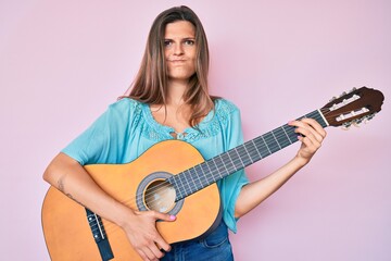 Fototapeta premium Beautiful caucasian woman playing classical guitar skeptic and nervous, frowning upset because of problem. negative person.