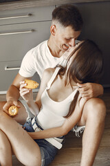 Cute couple in a kitchen. Lady in a white t-shirt. Pair at home eat boiled corn.