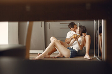 Cute couple in a kitchen. Lady in a white t-shirt. Pair at home eat boiled corn.