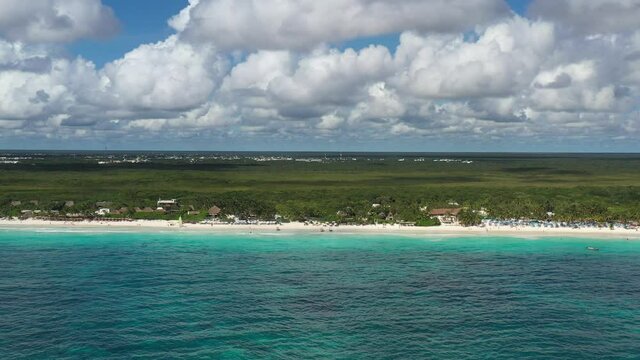 Espectacular vista a&eacute;rea de Playa Paraiso, en Tulum, M&eacute;xico. El drone volando de forma lateral a 150 metros de la costa con un cielo azul y nublado como fondo.