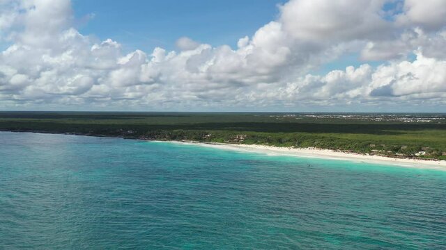 Vista a&eacute;rea panor&aacute;mica de Playa Para&iacute;so en Tulum, M&eacute;xico. El drone 120 metros dentro del mar y girando lentamente de izquierda a derecha con un cielo azul como fono.