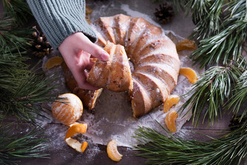 Homemade delicious christmas or new year cake with tangerines on a wooden background with coniferous branches