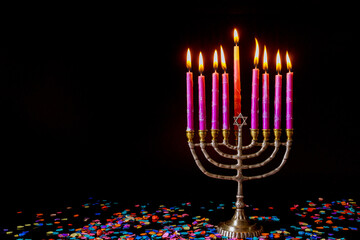 Pink candles on menorah and confetti on black background. Jewish holiday Hanukkah.