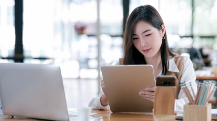 Beautiful businesswoman working on tablet computer while sitting in modern office.