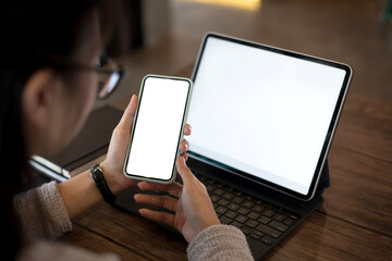 Young woman working mobile phone white blank screen and digital tablet. mock up. copy space