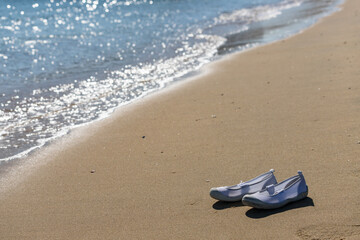 Fototapeta na wymiar リゾート地のビーチにある子供の上靴の風景