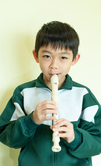 A young child is playing the flute. Art for kid. A little boy with a musical instrument. A music tuition lesson. Creative kid with the classical song education. © Natcharlai