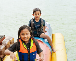 Fototapeta na wymiar Young boy enjoying water activities on banana boat at the Kenyir Lake, Terengganu, Malaysia.