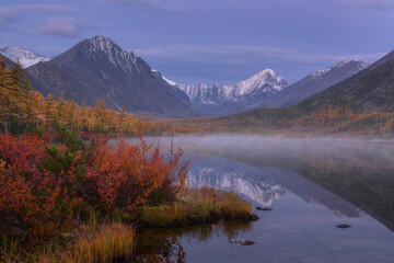 Light fog on a mountain lake on an autumn morning