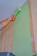 Green painting on a wooden cabinet furniture. Painting with roller. Selective focus. © ellinnur