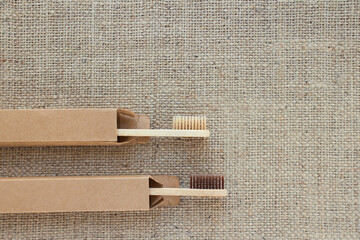 Mockup image of natural bamboo toothbrushes in paper packaging boxes on rustic background with copy...