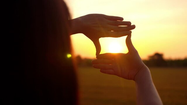Future planning concept, Woman hands making frame gesture with sunset, Female capturing the sunrise.