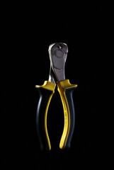 black and yellow pliers, wire cutters on black background