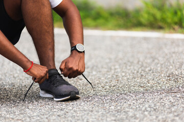 Close up Asian sport runner black man wear watch sitting he trying shoelace running shoes getting ready for jogging and run outdoor street health park with copy space, healthy exercise workout concept - obrazy, fototapety, plakaty