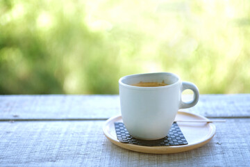 Obraz premium Hot coffee cup on wood table with blur nature background.