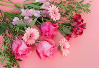 Bouquet of fresh scarlet roses, pink gerberas, and pink and red Alstroemeria on a pink background