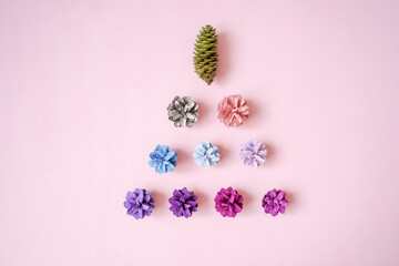 Christmas tree from Multi-colored pine cones on pink background, top view. Christmas and new year concept. Flat lay style.