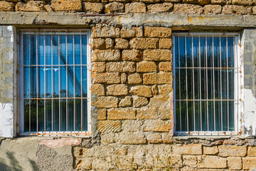 Fototapeta na wymiar Two windows with bars in an old house