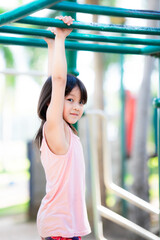 Active cute girl playing hanging outdoors. 5 years kid climbing bar at playground near by the...