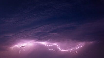 Fototapeta na wymiar Bright Lightning On Purple Night Sky During Hunderstorm