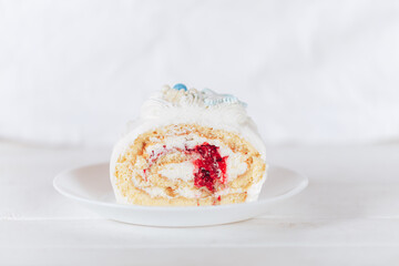 A cut piece from a white roll cake with a cherry filling on against a white background. Christmas mood. Sweets for any occasion.