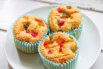 High angle view a group of mamon cake with sweet fruits topping on a a white wooden table.