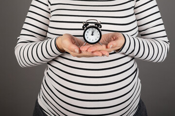 Pregnant woman holding a clock