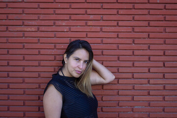 urban photo of elegant mexican woman in front of brick wall