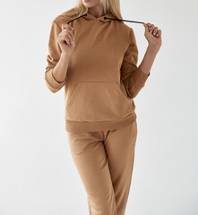girl wears light brown hoodie and pants. isolated photo of women wearing nude color fleece textile...