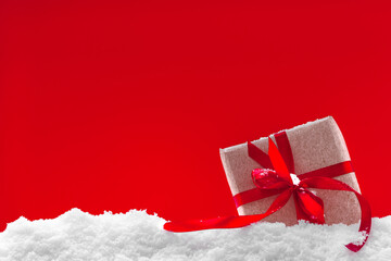Festive red Christmas background, white snowflakes and christmas present in snow