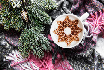 Coffee with a snowflake pattern on a warm woolen plaid