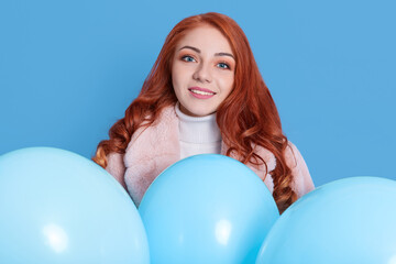 Beauty joyful female girl with helium balloons, having fun isolated over blue background, lady looking at camera with happy facial expression, girl celebrating positive event.