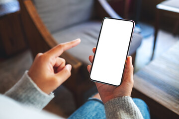 Mockup image of a woman holding and pointing finger at mobile phone with blank white desktop screen