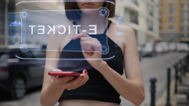 Unrecognizable young adult woman standing on the street interacts HUD hologram with text E-ticket. Girl in black clothes uses technology of the future mobile screen