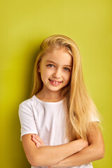 happy kid girl with long hair smiles at camera isolated on green background, people, children concept, human emotions