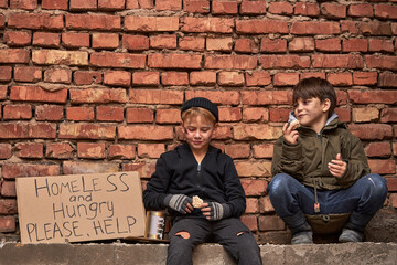 two desperate street children asking for help in dirty town, on street, hope for help and...