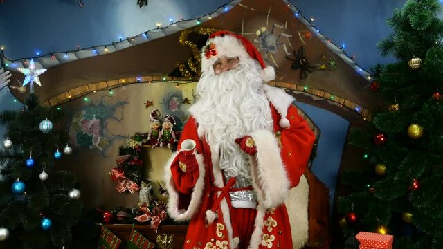 Jolly Santa is happily dancing near Christmas tree and ringing bell. The concept of joy and fun in Christmas holidays. Close-up or medium plan. Holiday.