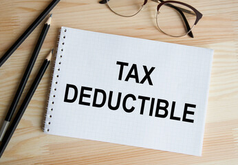 In the notebook the text OF TAX DEDUCTIBLE, next to pencils and glasses.