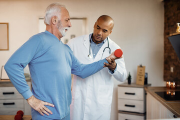 Senior man having physical therapy with African American doctor at nursing home.