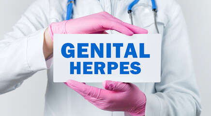 Cropped view of female doctor in a white coat and pink sterile gloves holding a card with words - GENITAL HERPES - obrazy, fototapety, plakaty