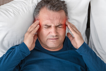 Mature man suffering from head ache in bed