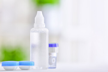 Containers with contact lenses and solution on blurred background