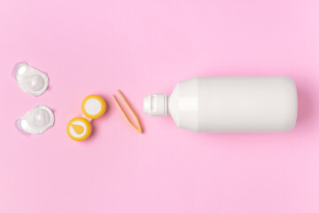 Container with contact lenses, solution and tweezers on color background