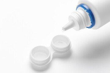 Container with contact lenses and  solution on white background