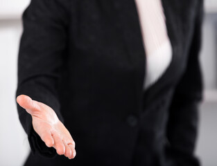 Obraz premium Woman office worker in black suit offering one's hand