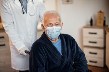 Fototapeta na wymiar Happy senior man wearing protective face mask at nursing home and looking at camera.