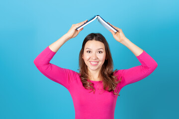 mock up, a young woman holding a diary or book over her head like a roof , isolated on a blue...