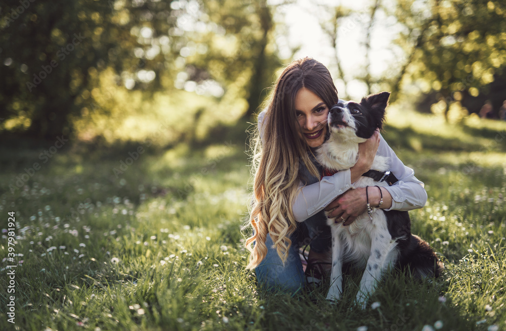 Wall mural beautiful woman with playful dog on fresh green meadow