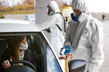 medical workers taking another person's in car temperature with a thermometer, . entrance control to a building, outdoors. pandemics and epidemics prevention.